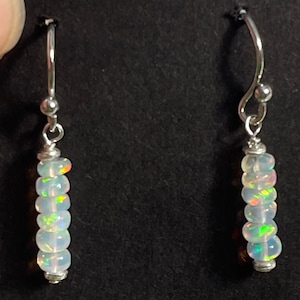 May include: A pair of silver dangle earrings with a row of iridescent white opal beads.