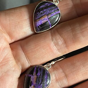 May include: A pair of silver dangle earrings with purple and black striped teardrop-shaped stones.