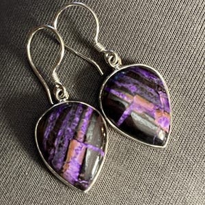May include: A pair of silver dangle earrings with purple and black striped gemstone drops.