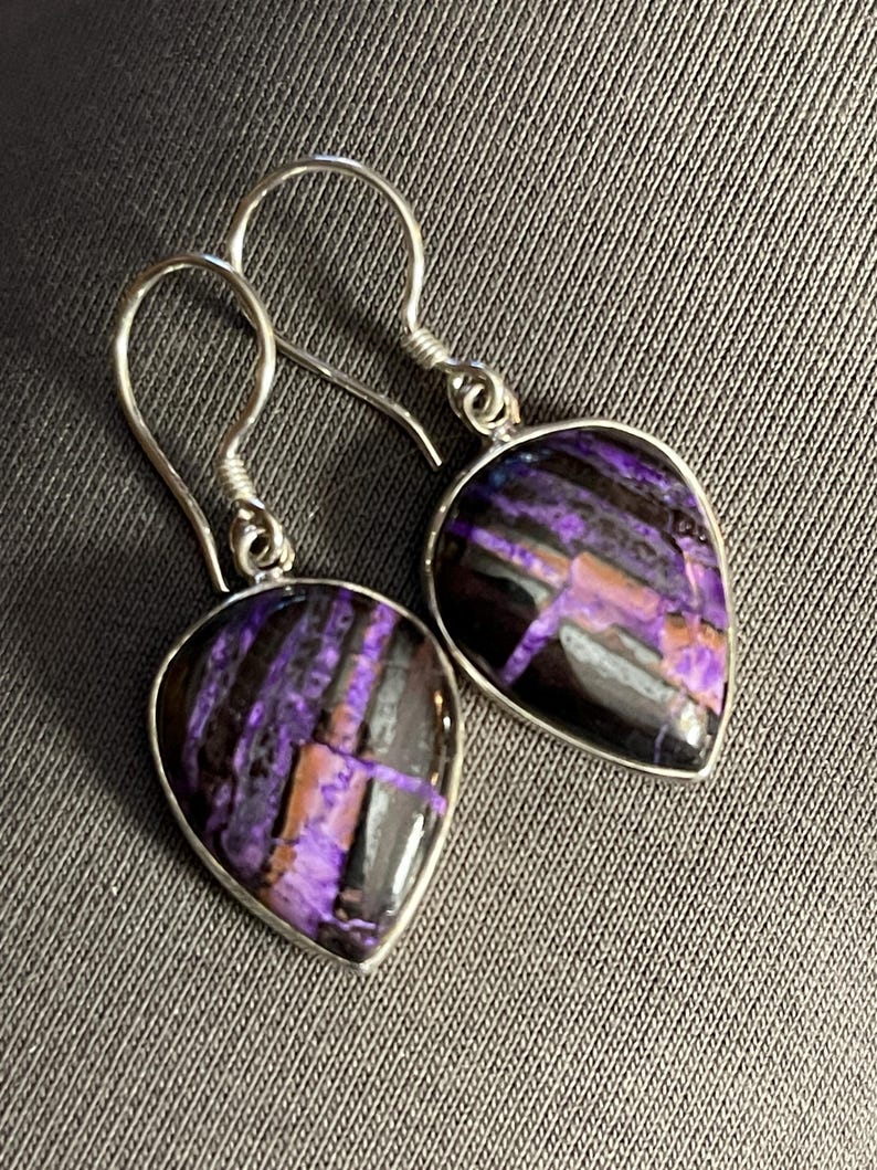 May include: A pair of silver dangle earrings with purple and black striped gemstone drops.