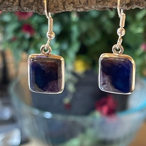 May include: A pair of silver earrings with square-shaped blue gemstone drops.