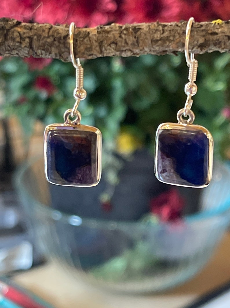 May include: A pair of silver earrings with square-shaped blue gemstone drops.