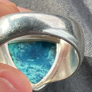 Puede incluir: Un anillo de plata con una piedra preciosa azul y verde engastada en forma triangular.