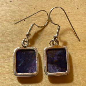 May include: A pair of silver earrings with square-shaped purple and silver stones.