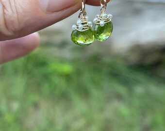 May include: A pair of gold earrings with green gemstone drops and a pearl accent.