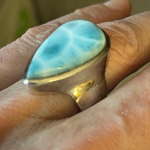 May include: A silver ring with a teardrop-shaped blue and white gemstone. The gemstone has a swirling pattern.