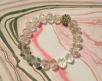 May include: A clear crystal bracelet with a sparkly silver bead in the center. The bracelet is made of faceted crystal beads and is strung on elastic.