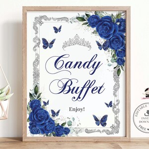 Op de afbeelding: Een ingelijst bord met een witte achtergrond, met de woorden "Candy Buffet" in elegant schrift. Het bord is versierd met blauwe rozen, vlinders en een zilveren tiara. De zin "Enjoy!" is ook opgenomen.