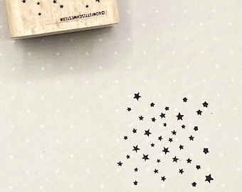 May include: A wooden stamp with a design of a scattering of black stars. The stamp is labeled "Konfetti Sterne".