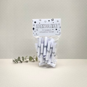 May include: A white plastic bag filled with rolled up white paper notes. The bag has a label that says "Adventskalender 24 Gedanken voll positiver Energie".