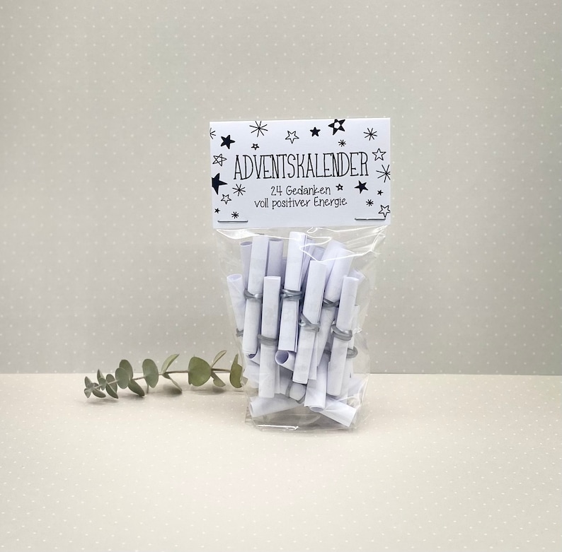 May include: A white plastic bag filled with rolled up white paper notes. The bag has a label that says "Adventskalender 24 Gedanken voll positiver Energie".