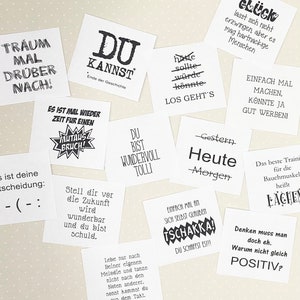 May include: A collection of motivational and inspirational quotes printed on white square cards. The quotes include phrases like "You can do it", "Dream big", and "Never give up".