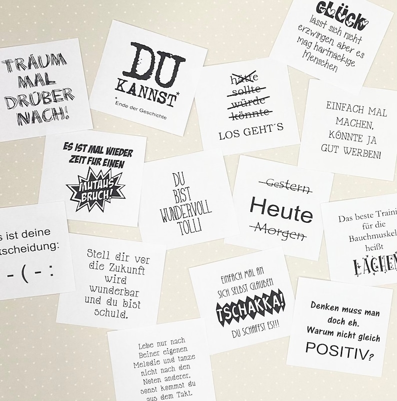 May include: A collection of motivational and inspirational quotes printed on white square cards. The quotes include phrases like "You can do it", "Dream big", and "Never give up".