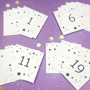May include: A set of white cards with black numbers and stars printed on them. The numbers range from 1 to 19. The cards are on a purple background.