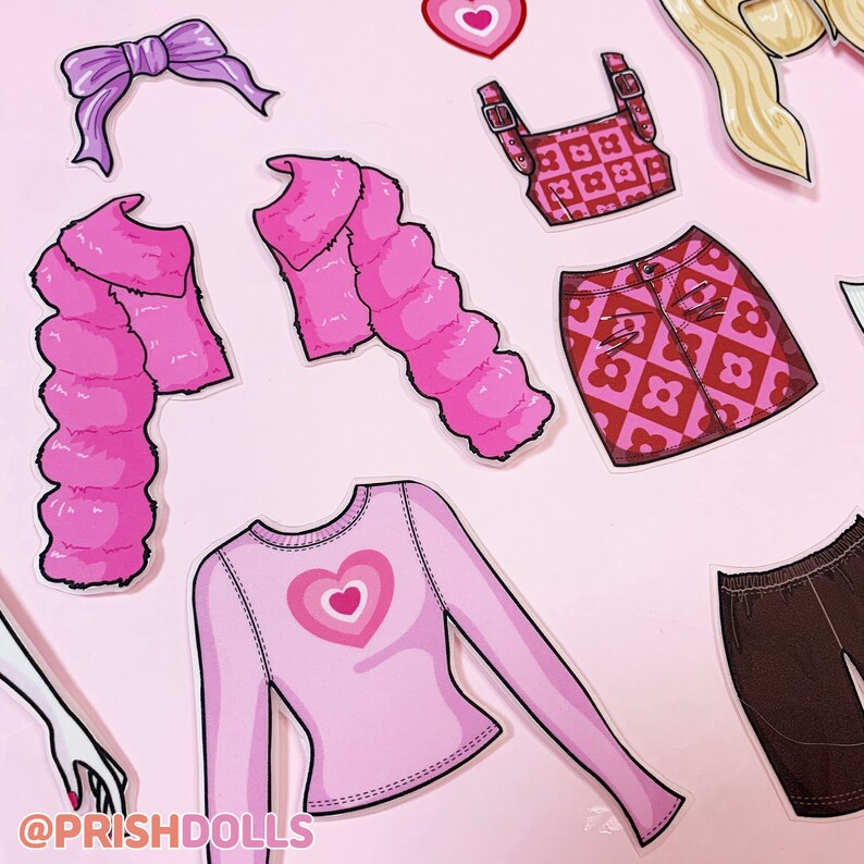 May include: A set of pink and red paper doll clothes with a heart design. The set includes a fluffy jacket, a long-sleeved shirt, a skirt, a crop top, a headband, and a pair of trousers. The text "@PRISHDOLLS" is at the bottom of the image.