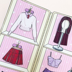 May include: A pink and white closet with three shelves. The top shelf has a white sweater with a collar and a bow tie. The middle shelf has a red and black plaid skirt. The bottom shelf has a purple top with a bow. The closet is decorated with small white flowers.