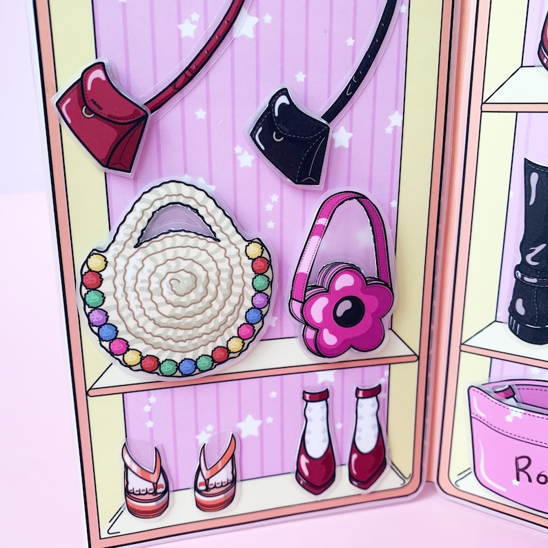 May include: A paper doll wardrobe featuring various accessories. Includes a red purse, a black purse, a straw tote bag with colorful beads, a pink flower-shaped purse, sandals, and red and white shoes. The background is pink with white stars.