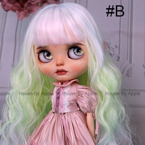 May include: A doll with long, wavy, green and white hair, wearing a pink dress with white lace trim. The doll has large, blue eyes with glitter accents. The doll is looking to the right of the image.