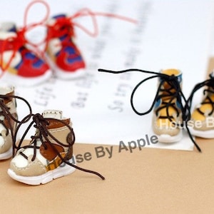 May include: Miniature sneakers in various color schemes, including red, blue, yellow, and brown. Each pair features white soles and laces, with a focus on detail. The sneakers are designed for a doll or craft project.