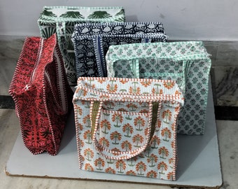 May include: A collection of quilted tote bags in various colors and patterns. The bags feature floral and geometric designs in red, green, blue, and white. Each bag has a zipper closure and handles, with a consistent stitch pattern.
