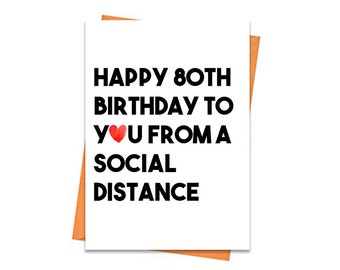 Puede incluir: Tarjeta de felicitación blanca con el texto "HAPPY 80TH BIRTHDAY TO YOU FROM A SOCIAL DISTANCE" en negro. Un corazón rojo reemplaza la palabra "LOVE". La tarjeta está sobre un sobre naranja.