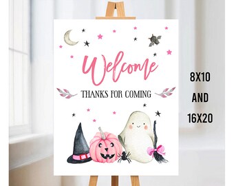 Puede incluir: Señal de bienvenida con temática de Halloween en rosa y negro. La señal dice "Bienvenido Gracias por venir" con un fantasma, una calabaza y un sombrero de bruja. Disponible en 8x10 y 16x20.