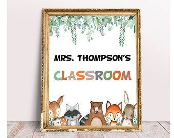 May include: A classroom door sign with a gold frame and a white background. The sign says "Mrs. Thompson's Classroom" in black text. There are watercolor illustrations of leaves, a deer, a raccoon, a bear, a fox, and a rabbit.
