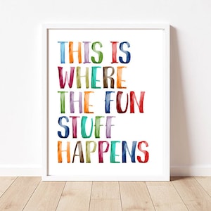May include: A white framed print with the text "This is where the fun stuff happens" in colorful watercolor lettering.