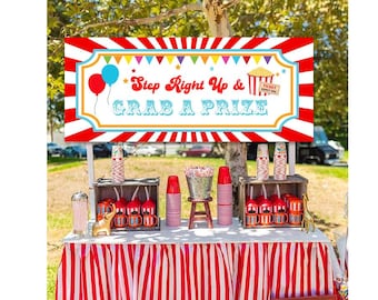 Puede incluir: Una pancarta roja y blanca a rayas con el texto "Step Right Up & Grab A Prize" en azul y blanco. La pancarta está colgada sobre una mesa con un mantel a rayas rojas y blancas. Hay varias tazas rojas y blancas y una figurita de elefante dorada sobre la mesa.