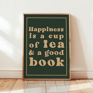 May include: A framed print with a green background and gold text that reads "Happiness is a cup of tea & a good book".