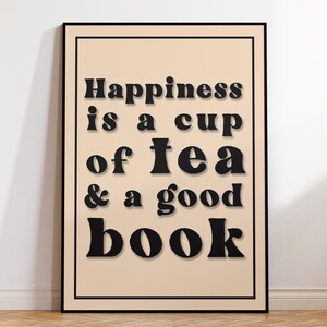 May include: A black framed print with a beige background and the text "Happiness is a cup of tea & a good book" in black.