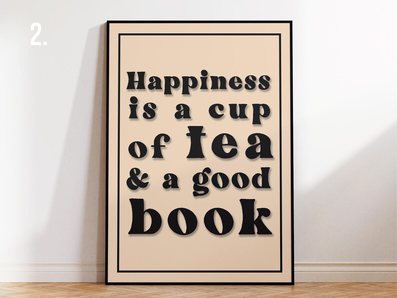 May include: A black framed print with a beige background and the text "Happiness is a cup of tea & a good book" in black.