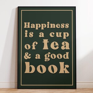 May include: A dark green framed poster with the text "Happiness is a cup of tea & a good book" in a light brown font.