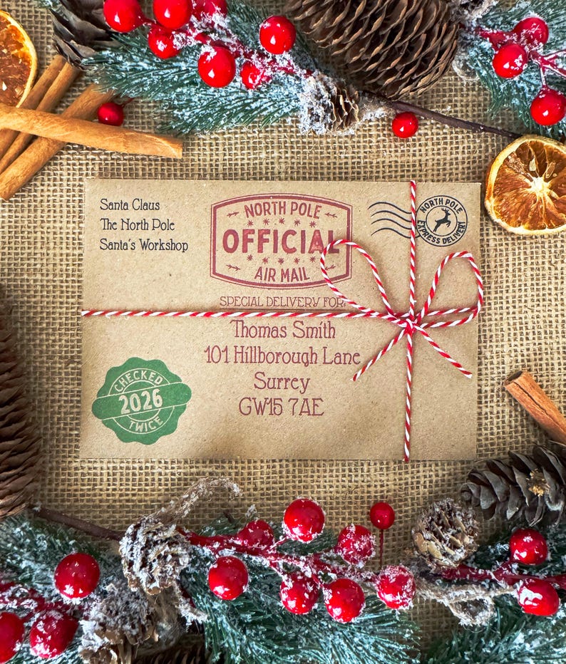 Peut inclure: Une enveloppe rectangulaire en papier kraft adress&eacute;e &agrave; Thomas Smith, 101 Hillborough Lane, Surrey, GW15 7AE. Elle porte un tampon rouge North Pole Official Air Mail, un sceau vert Checked Twice 2026 et une ficelle rouge et blanche nou&eacute;e.