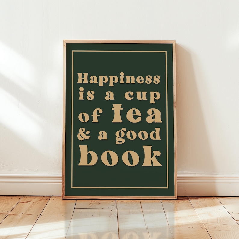 May include: A framed print with a green background and gold text that reads "Happiness is a cup of tea & a good book".