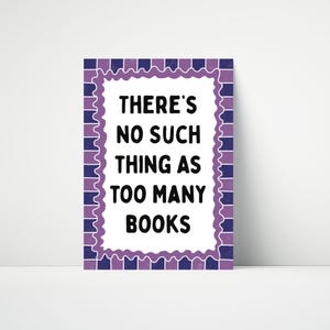 May include: A rectangular sign with the text "THERE'S NO SUCH THING AS TOO MANY BOOKS" in black. The sign has a white background with a purple and blue decorative border.