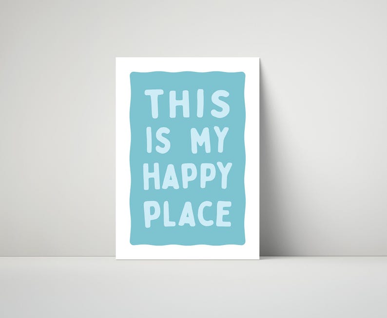 Pu&ograve; includere: Una stampa artistica incorniciata con le parole "THIS IS MY HAPPY PLACE" in lettere maiuscole blu chiaro su sfondo azzurro. La stampa &egrave; esposta su una superficie bianca.