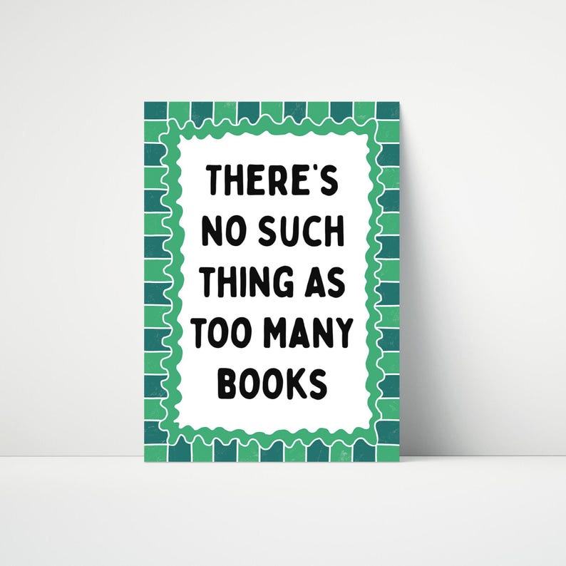 May include: A rectangular sign with a white background and a green scalloped border. The text "THERE'S NO SUCH THING AS TOO MANY BOOKS" is in bold black font. The sign is a decorative item.