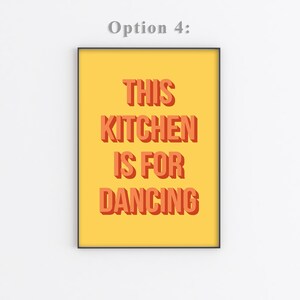 May include: A yellow poster with black frame featuring the text "This Kitchen is for Dancing" in orange letters with a 3D effect.