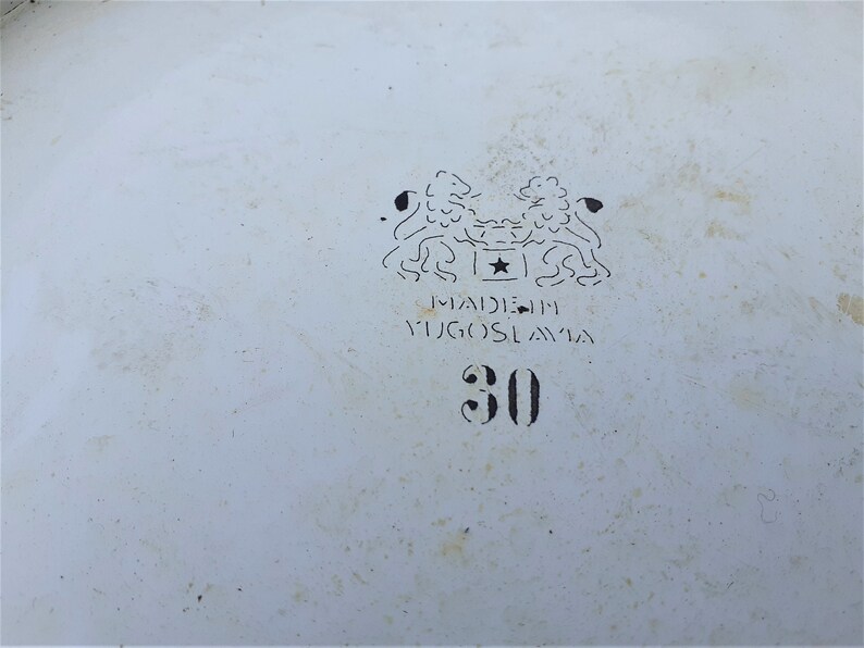 Puede incluir: Un taz&oacute;n de esmalte blanco con un logotipo en blanco y negro que dice "Hecho en Yugoslavia" y el n&uacute;mero "30".
