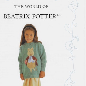 May include: A green children's sweater with a knitted image of a pig wearing a red jacket and holding a walking stick. The sweater is part of a collection called "The World of Beatrix Potter."