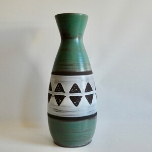 Könnte beinhalten: Eine grüne Keramikvase mit einem weißen und schwarzen geometrischen Muster. Die Vase hat einen schmalen Hals und einen breiten Boden.
