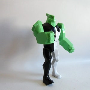 Könnte beinhalten: Eine grüne, schwarze und weiße Actionfigur eines Superhelden-Charakters. Die Figur hat einen grünen Kopf und Arme, einen schwarzen Torso und ein Bein sowie einen weißen Torso und ein Bein. Die Figur steht in einer dynamischen Pose.