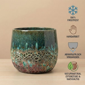 May include: A ceramic planter with a glossy finish. The planter has a dark teal top that fades into a textured, porous, brown and red base. The planter is handmade and frost-resistant.