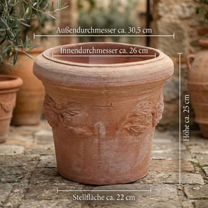 Może przedstawiać: Terakotowa donica z szerokim rantem i wytłoczonymi wzorami liści. Donica ma około 30,5 cm średnicy, 25 cm wysokości i podstawę około 22 cm. Średnica wewnętrzna wynosi około 26 cm.