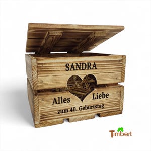 Puede incluir: Una caja de madera con tapa con bisagras, con el nombre "SANDRA" y las palabras "Alles Liebe zum 40. Geburtstag" con un recorte en forma de corazón. La caja está llena de paja.