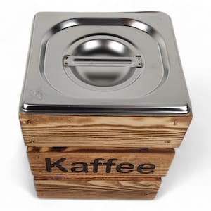 May include: A wooden box with a stainless steel lid, labeled "Kaffee". The box is made of natural wood with a rustic finish.
