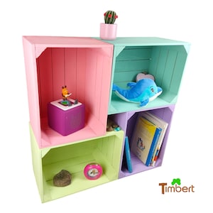 Può includere: Un set di quattro casse di legno colorate impilate per creare un'unità a scaffale. Le casse sono dipinte in rosa, verde, azzurro e viola. Gli scaffali sono decorati con un piccolo giocattolo, un delfino di peluche e libri.