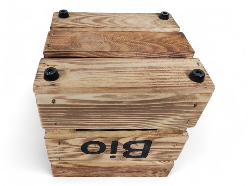 May include: A wooden box with a black label that says "Bio!" The box is made of natural wood and has a rustic look. It has black rubber feet on the bottom.