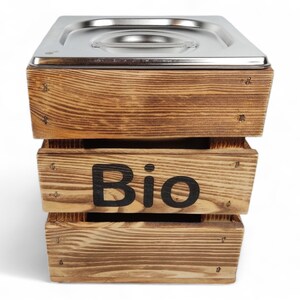 May include: A wooden compost bin with a stainless steel liner. The bin has the word "Bio" printed on the front.